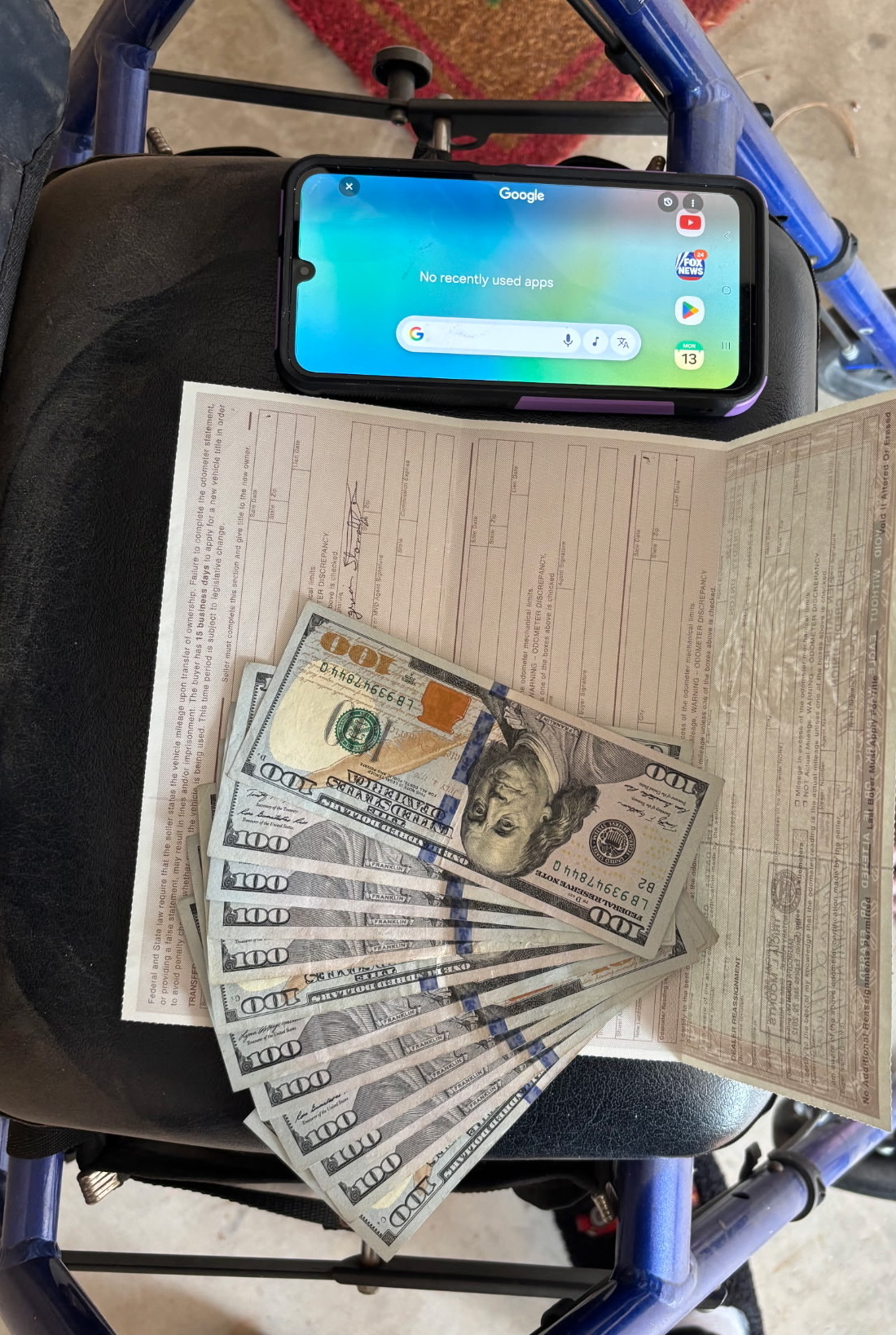 Stack of $100 bills paid in cash on top of a signed Nevada vehicle title — real Cash For Cars Vegas NV transaction